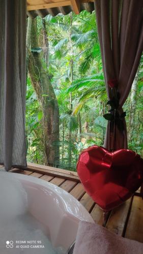 a bath tub with a window looking out at a forest at Vila Paraíso in Blumenau
