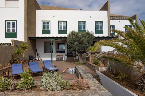 une maison avec deux chaises longues bleues dans une cour dans l'établissement Villa El Olivo - first line with direct access to the beach, à Poris de Abona