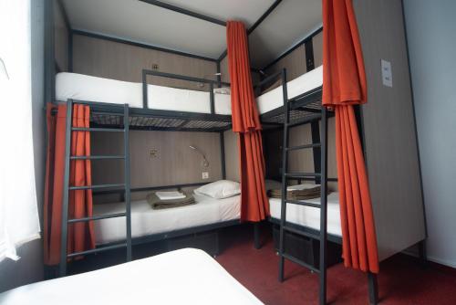 Zimmer mit 2 Etagenbetten und orangefarbenen Vorhängen in der Unterkunft City Inn Paris in Paris