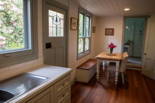 uma cozinha com um lavatório e uma mesa com um vaso de flores em Ard Choille Cottages em Mount Macedon