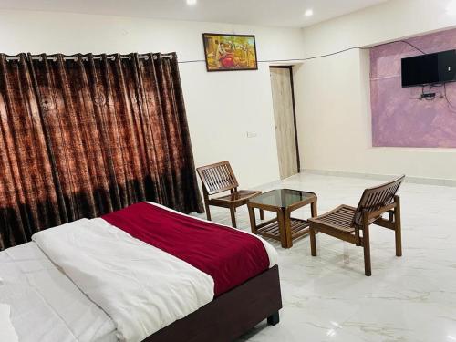 a bedroom with a bed and two chairs and a table at OYO Zora Luxury Rooms in Visakhapatnam