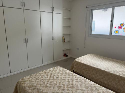 耶爾瓦布埃納的住宿－Departamento de dos dormitorios y terraza con asador，一间卧室设有两张床、白色橱柜和窗户。