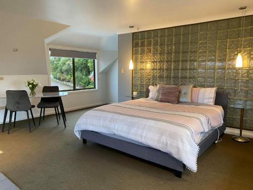 Un dormitorio con una cama y un escritorio y una ventana. en Gordon Gateway, en Strahan