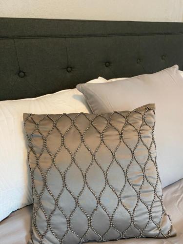 a pillow sitting on a bed with white pillows at Charming City Bungalow in Jacksonville