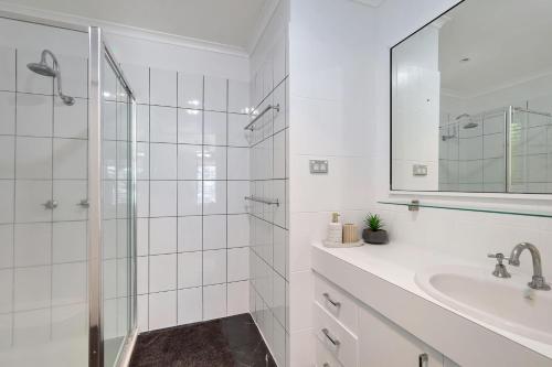 uma casa de banho branca com um chuveiro e um lavatório. em Salonika Sands em Hay Point