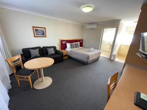a room with a couch and a bed and a table at George Bass Motor Inn in Nowra