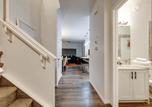 a hallway with stairs and a bathroom with a sink at Stylish/4Bedroom/FreeParking/IndoorFirePlace in Calgary