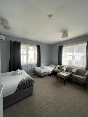 a bedroom with two beds and a couch and chairs at Mountain View Motel in Queenstown