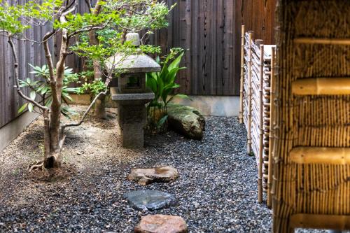 a garden with a bird bath and a fence at Rinn Premium Machiya Yae in Kyoto