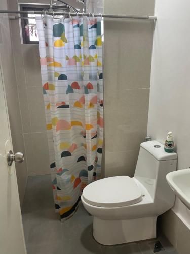 a bathroom with a toilet and a shower curtain at WV Tower 1 Studio in Iloilo City