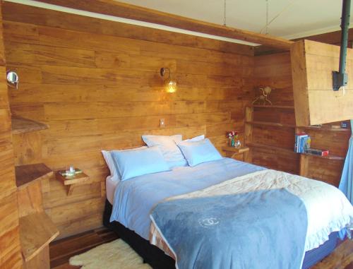 a bedroom with a bed with wooden walls at Raglan's Tranquil Garden Retreat - Moa Stone Lodge in Raglan