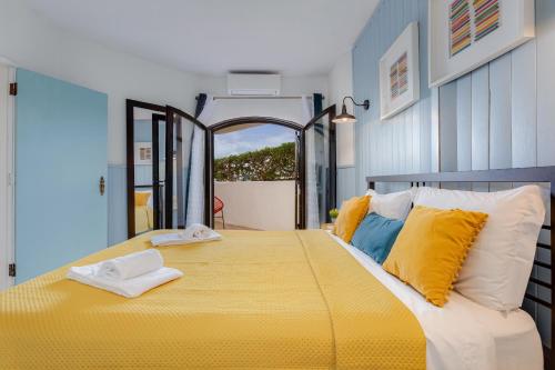 ein Schlafzimmer mit einem großen gelben Bett mit gelben Kissen in der Unterkunft Casa Flor de Sal Apartment in Carvoeiro