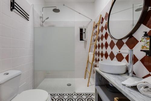 ein Badezimmer mit einem Waschbecken, einem WC und einem Spiegel in der Unterkunft Casa Flor de Sal Apartment in Carvoeiro