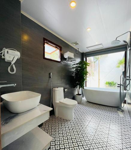a bathroom with a tub and a toilet and a sink at Sol Inn - Moc Chau in Mộc Châu