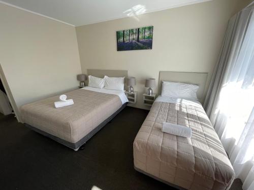 a bedroom with two beds and a window at George Bass Motor Inn in Nowra