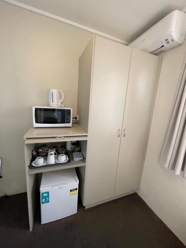 a small kitchen with a microwave and a refrigerator at George Bass Motor Inn in Nowra
