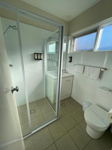 a bathroom with a toilet and a glass shower at George Bass Motor Inn in Nowra