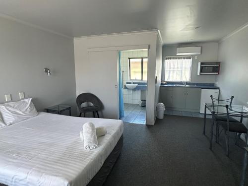 a bedroom with a bed and a bathroom with a sink at Eastland Pacific Motor Lodge in Opotiki