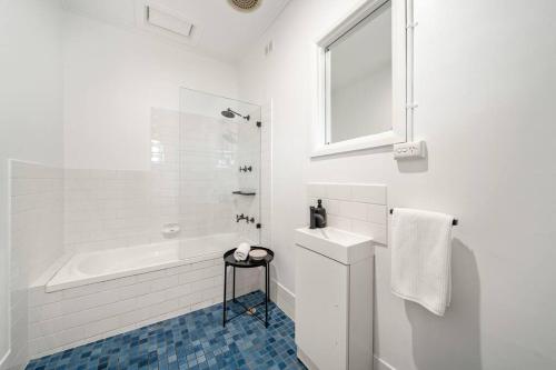 La salle de bains blanche est pourvue d'une baignoire et d'un lavabo. dans l'établissement Pier 36 Glenelg - WiFi, Family Friendly, à Glenelg