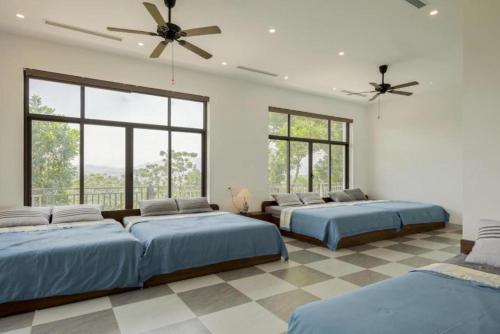 a bedroom with three beds and a ceiling fan at Mây Trắng Farmstay Villas Venuestay in Ba Vì