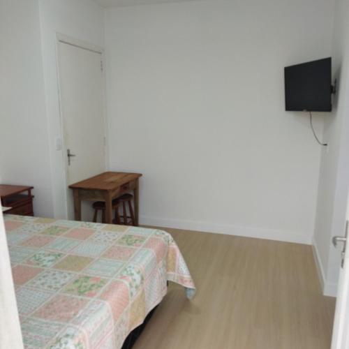 1 dormitorio con cama, mesa y TV en Suíte com entrada Privativa en Barra Velha