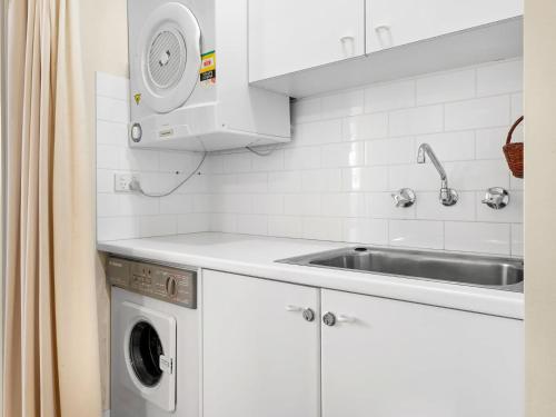 uma cozinha com um lavatório e uma máquina de lavar roupa em Aspect 2 em Thredbo