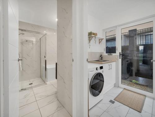 a white bathroom with a washing machine and a shower at Alloura 2 in Jindabyne