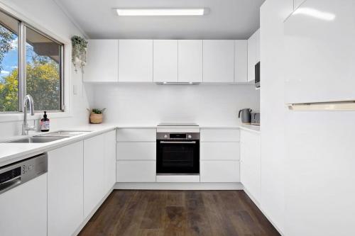 a kitchen with white cabinets and a sink and a window at Alpine Snowgums 1 in Jindabyne