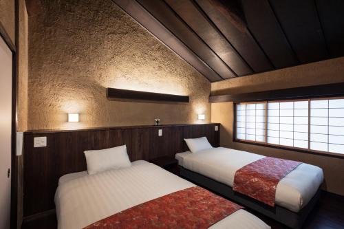 Una pequeña habitación con dos camas y una ventana. en Rinn Premium Machiya Kunpu, en Kioto