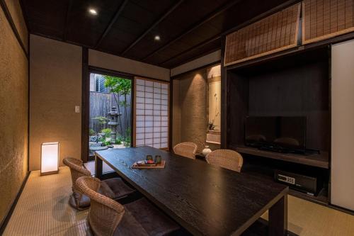 a dining room with a large wooden table and chairs at Rinn Premium Machiya Kunpu in Kyoto