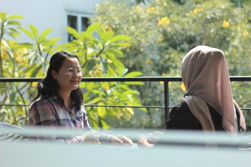 a woman sitting at a table with a woman wearing a hijab at Bale Ocasa by Behomy in Tangerang