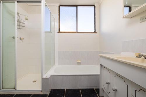 a bathroom with a shower and a tub and a sink at Bere Pad in Jindabyne