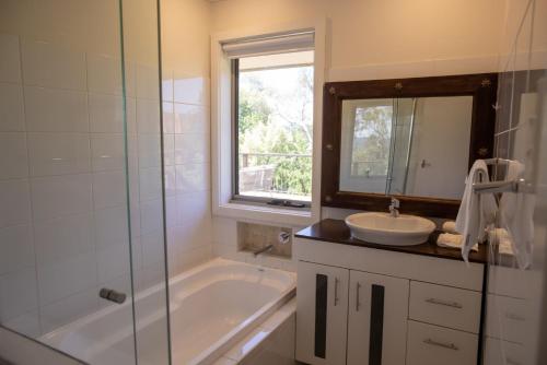 a bathroom with a tub and a sink and a mirror at Bogong Arms in Jindabyne