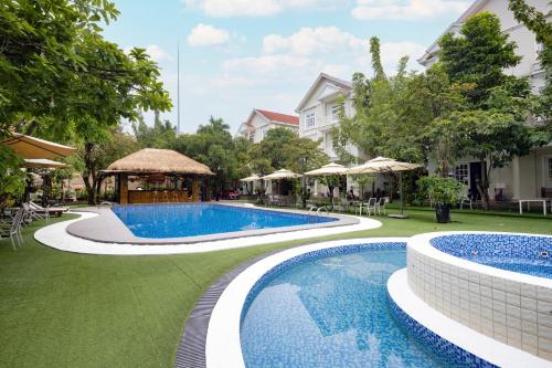 Hidden Mansions Saigon Resort في مدينة هوشي منه: منتجع فيه مسبحين و شرفة