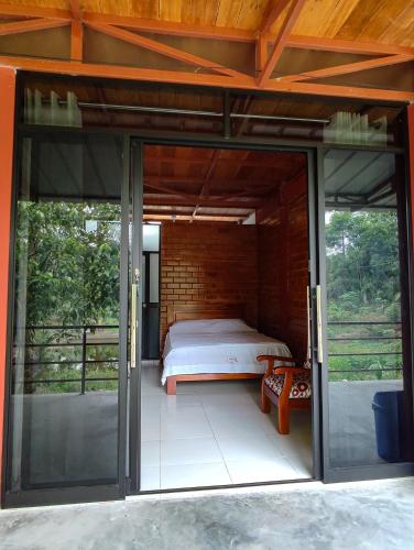 Zimmer mit einem Bett und Glasschiebetüren in der Unterkunft Cabañas Ecowasi in Tingo María