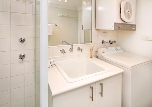 a white bathroom with a sink and a mirror at Central Abode in Jindabyne