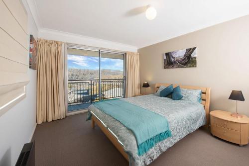 a bedroom with a bed and a large window at Erulisse in Jindabyne