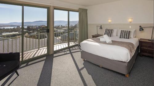 a bedroom with a bed and a balcony with a view at Glacialis 6 in Jindabyne