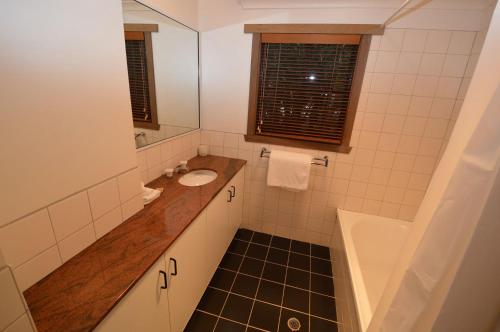 a bathroom with a sink and a tub and a mirror at Hi Plains Garadyigan Chalet in Thredbo
