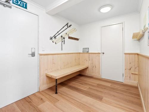 a wooden bench in a room with a door at Inala 7 in Thredbo