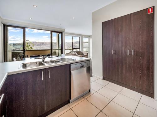 a kitchen with wooden cabinets and a large window at Jasper 1 in Jindabyne