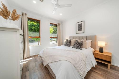 a white bedroom with a bed and two windows at Chalfont Way @ Glengowrie - WiFi BBQ Family in Somerton Park