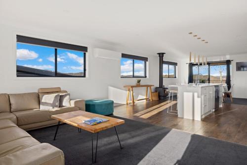 a living room with a couch and a table at Mountain G O A T - Wood Fired Hot Tub, Pool Table, Bike Storage, Ski Drying Room, Perfect for biking or ski trips! in Jindabyne