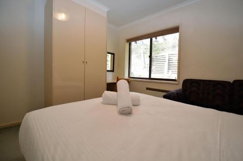 a bedroom with a white bed with a towel on it at Mowamba D5 in Thredbo