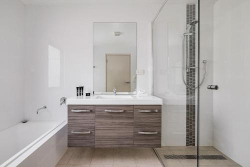 Un baño blanco con lavabo y ducha. en Moongate, en Jindabyne