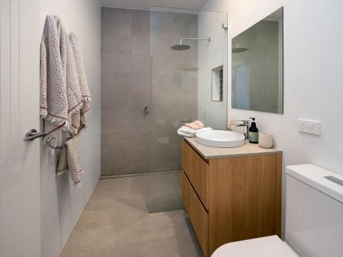 a bathroom with a sink and a toilet and a shower at Puggle Lodge in Jindabyne