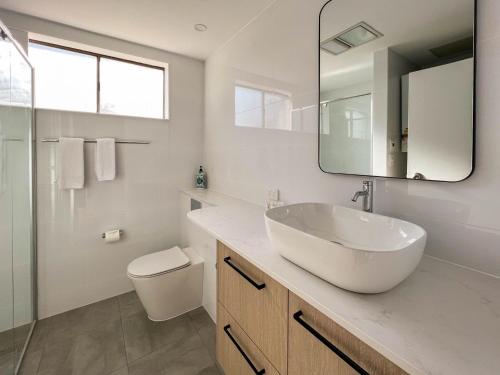 a white bathroom with a sink and a mirror at St Moritz 11 in Jindabyne