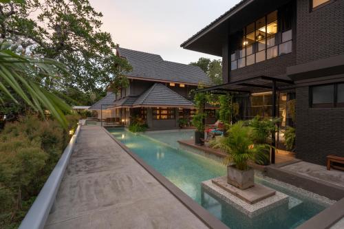 uma casa com piscina ao lado de um edifício em Phrip Phri Luxury Pool Villas em Phetchaburi