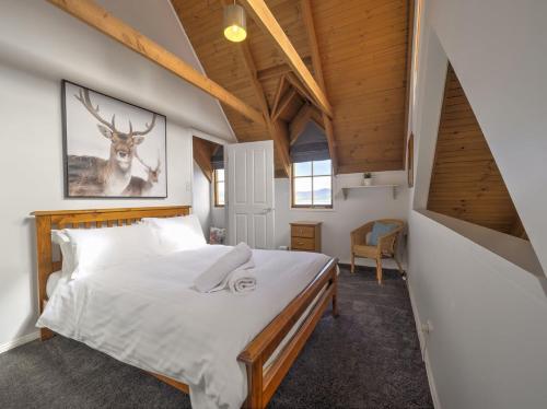 a bedroom with a bed with a deer picture on the wall at Tulong LakEscape in Jindabyne