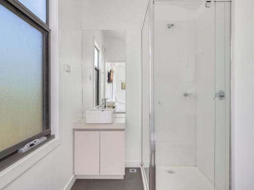 a white bathroom with a shower and a sink at Alpine Freedom in Jindabyne